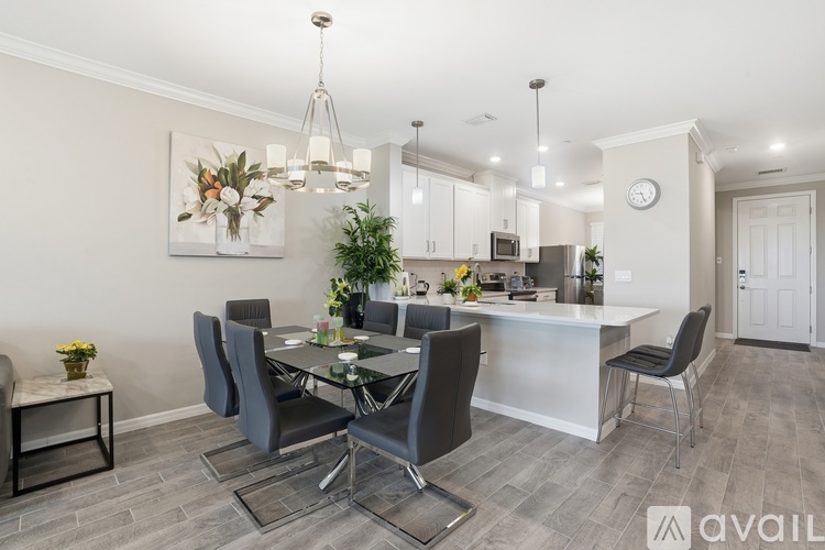 A modern dining room with a glass table and grey chairs.