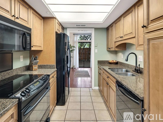 A kitchen with black appliances and wooden cabinets.