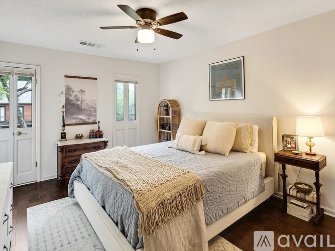 A bedroom with a bed, a ceiling fan, and a nightstand with a lamp.