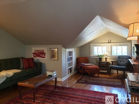 A living room with a green couch and a red rug.
