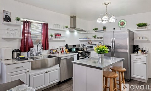 A kitchen with white cabinets and a large island with a flower vase on it.