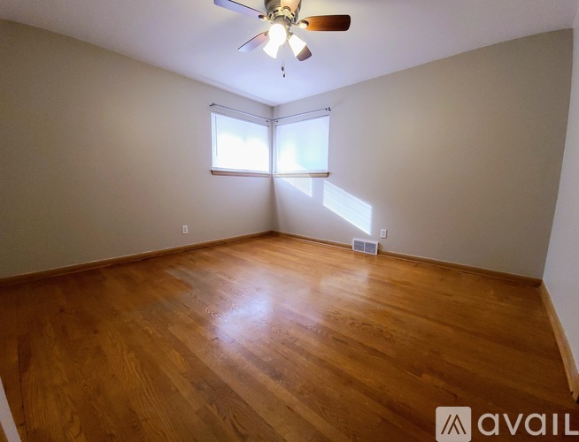 A room with wooden flooring and a ceiling fan.