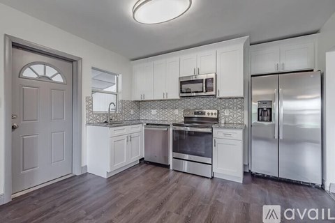 A kitchen with white cabinets and stainless steel appliances is available for rent.