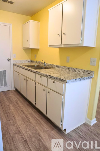 A kitchen with yellow walls and white cabinets.
