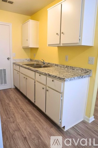 A kitchen with yellow walls and white cabinets.