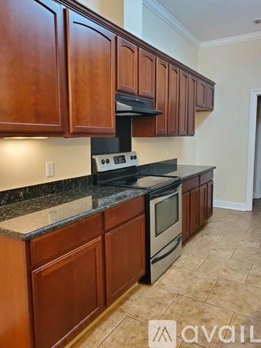 A kitchen with brown cabinets and black appliances.