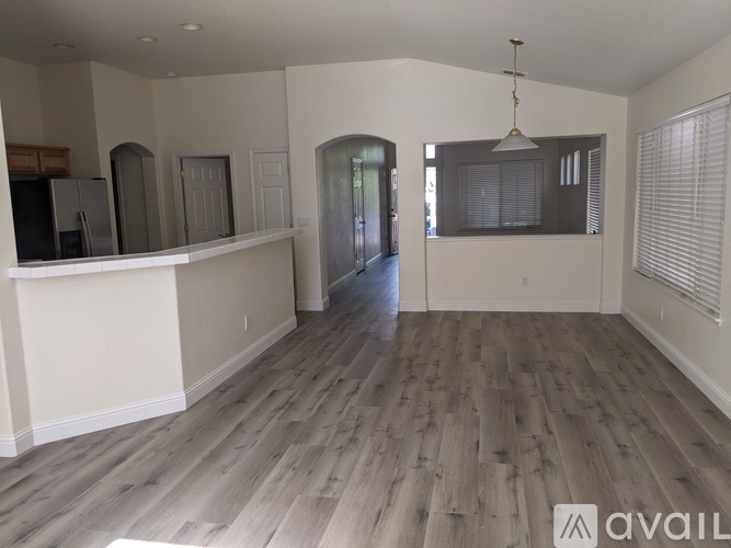 A spacious living room with wood flooring and a large window.
