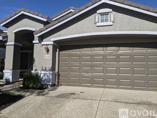 A house with a garage door and a window is numbered 5430.