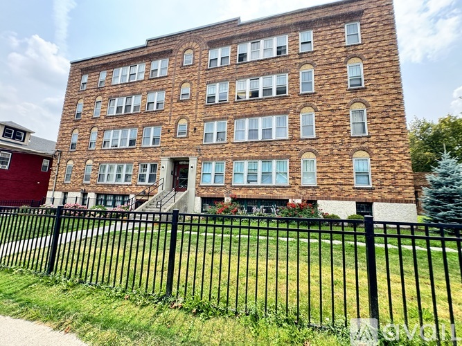 A large brick building with a black fence in front.