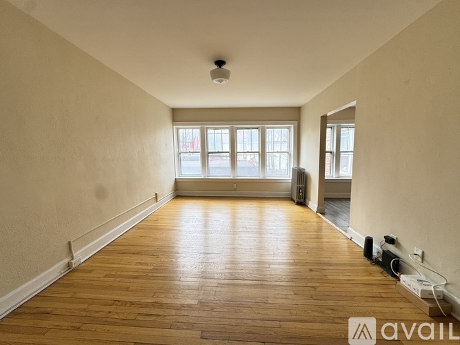 A spacious room with wooden flooring and a window.