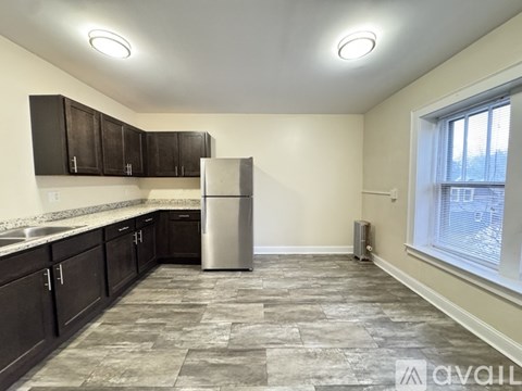 A kitchen with a refrigerator, sink, and cabinets.