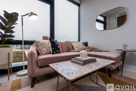 A living room with a pink sofa, a round mirror, and a table with a book on it.