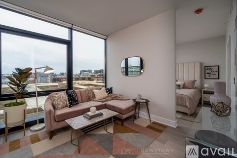 A living room with a couch, chair, and a large window overlooking the city.
