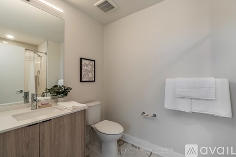 A bathroom with a toilet, sink, mirror, and towel rack.
