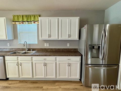 A kitchen with white cabinets and a stainless steel refrigerator.