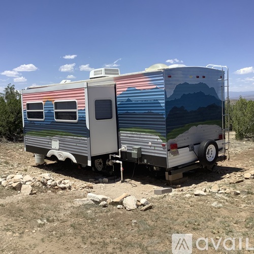 A silver and blue RV is parked in a rocky area.
