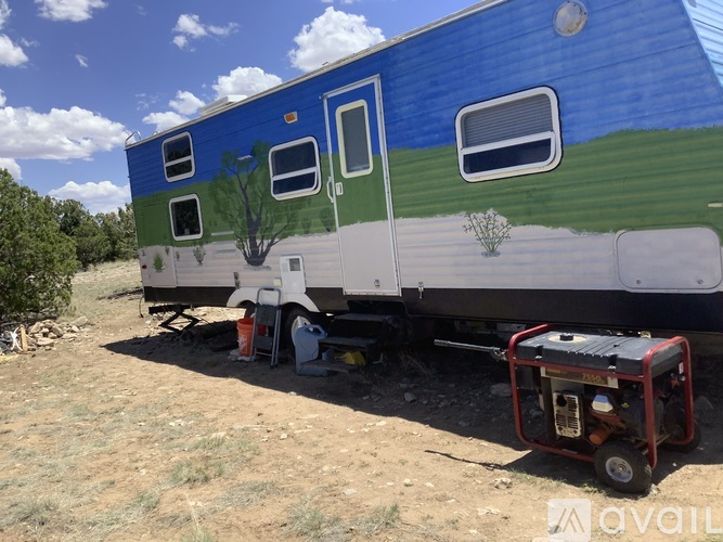 A blue and white train car with a tree painted on the side is parked in a field.