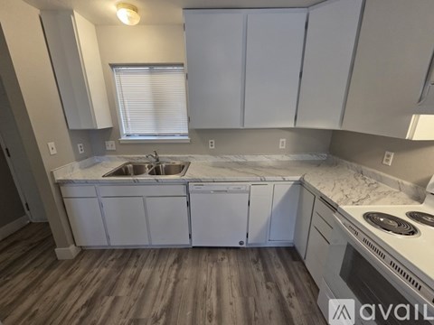 A kitchen with white cabinets and a marble countertop.