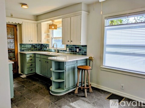 A kitchen with a green island and white cabinets.