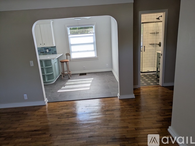 A room with wooden floors and a window with a chair in front of it.