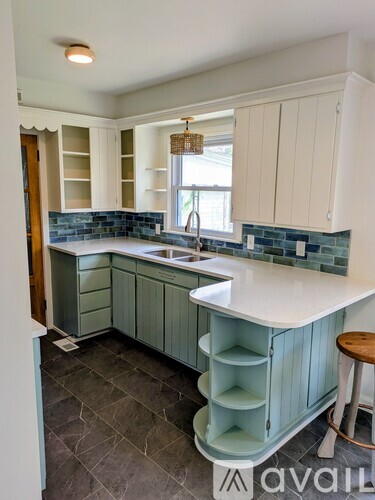 A kitchen with a white counter and green cabinets.