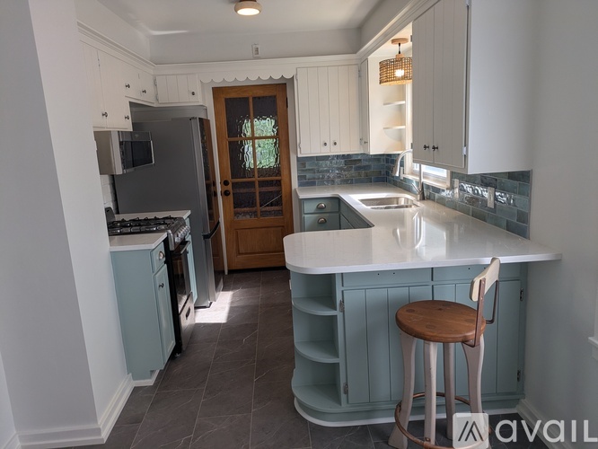 A kitchen with a white island and a wooden stool.