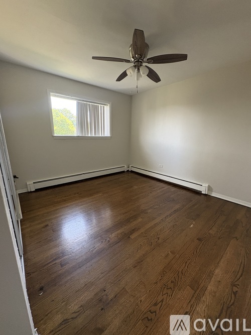 A room with wooden flooring and a ceiling fan.