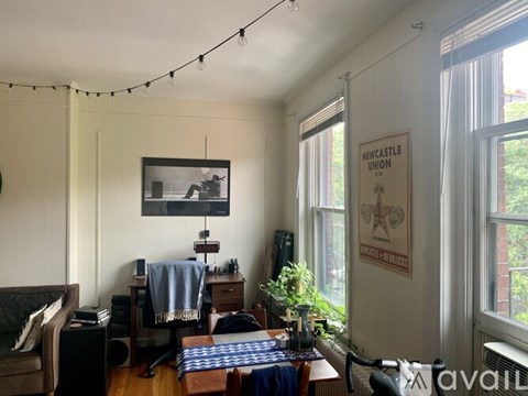 A living room with a couch, chair, and a table with a blanket on it.