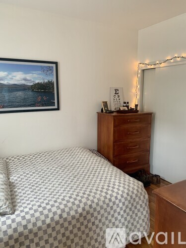 A bedroom with a bed, a dresser with a mirror and a picture frame on it.