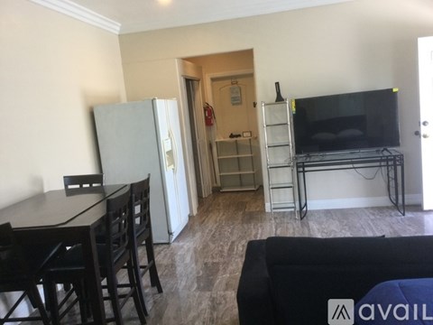 A living room with a black couch, a television, and a dining table with chairs.