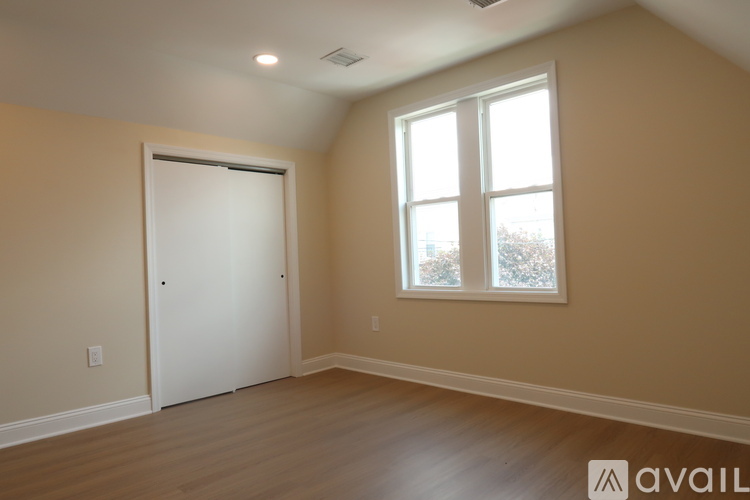 A room with a white door and a window with a view of trees outside.