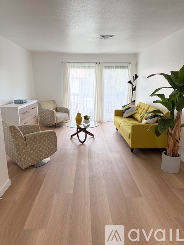 A living room with a yellow couch and a wooden floor.
