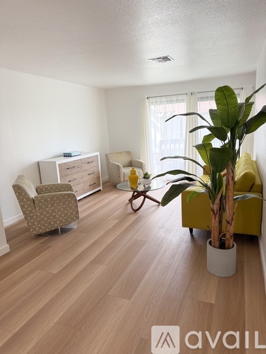A living room with a yellow couch and a plant in a white pot.