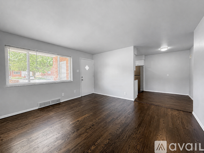 A room with wooden floors and white walls, with a window showing an outdoor view.