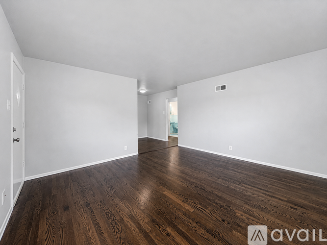 A spacious room with wooden flooring and white walls.