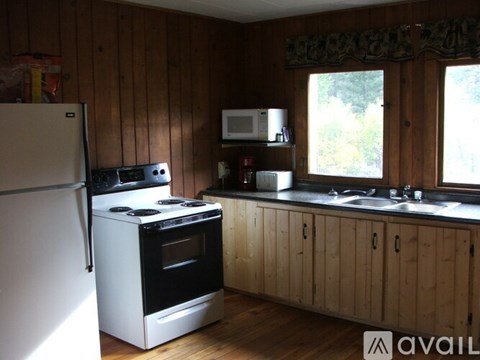 A kitchen with wooden walls and a white fridge.