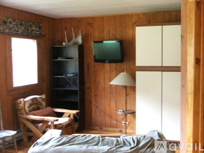 A bedroom with a bed, chair, and a tv mounted on the wall.