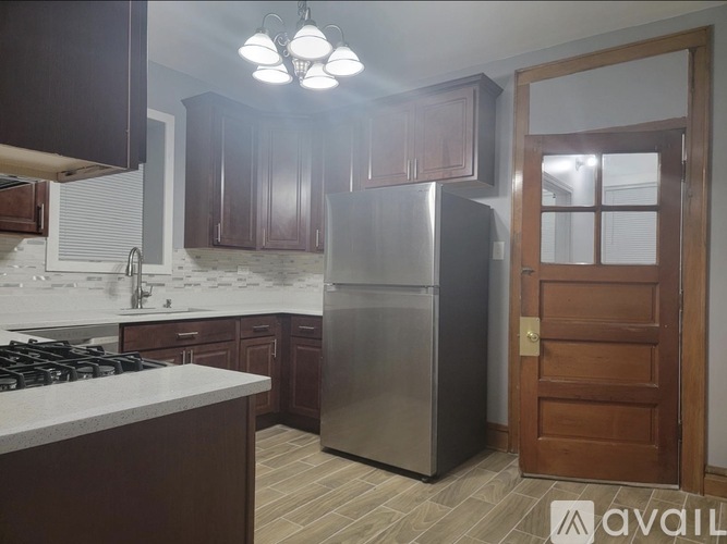 A kitchen with a stainless steel refrigerator and wooden cabinets.