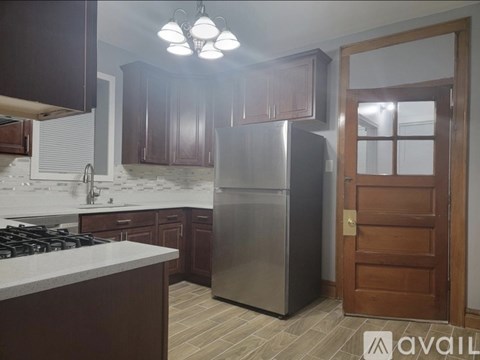 A kitchen with a stainless steel refrigerator and wooden cabinets.