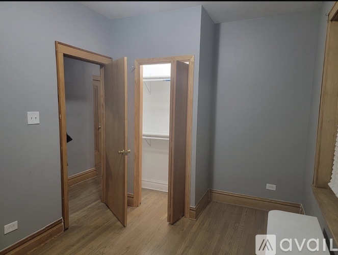 A room with a wooden floor and grey walls with two open doors.