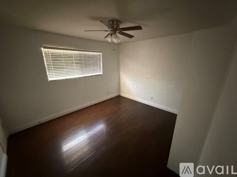 A room with a ceiling fan and a window with blinds.