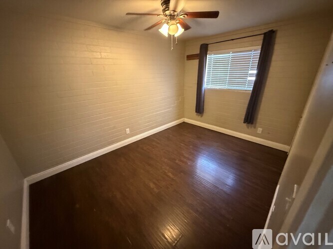 A room with a ceiling fan and wooden flooring.