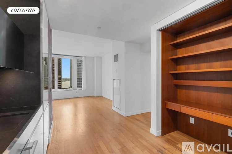 A spacious room with wooden flooring and a television on the left side.