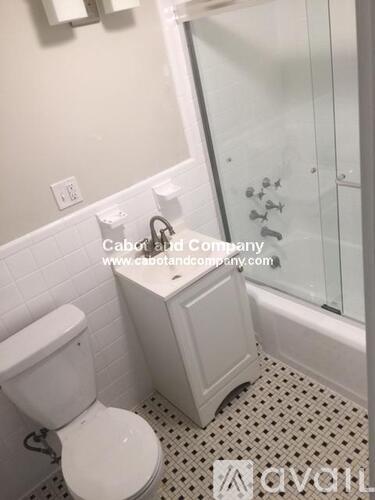 A white toilet sits next to a white cabinet in a bathroom.