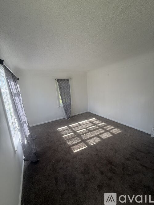 A room with a carpeted floor and a window with curtains.