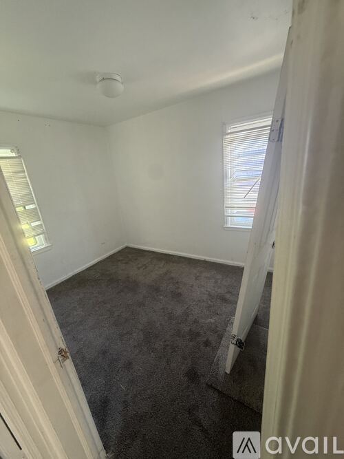 A room with a carpeted floor and a window with blinds.