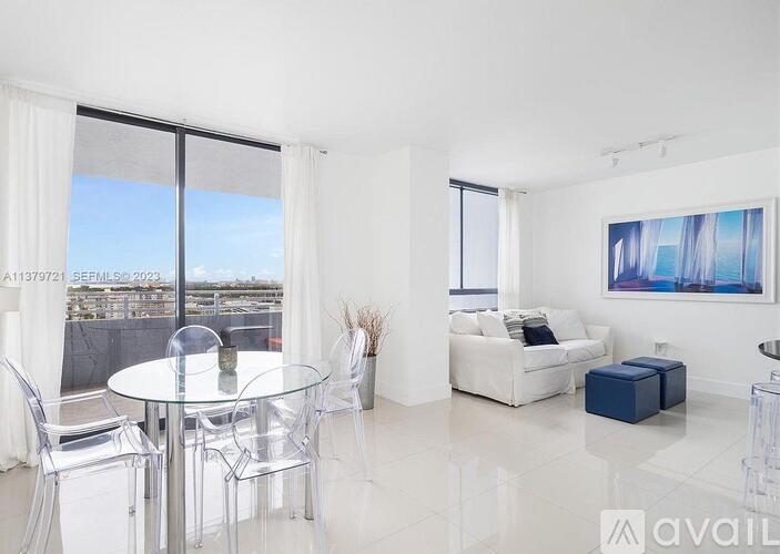 A modern living room with a glass table and white furniture.