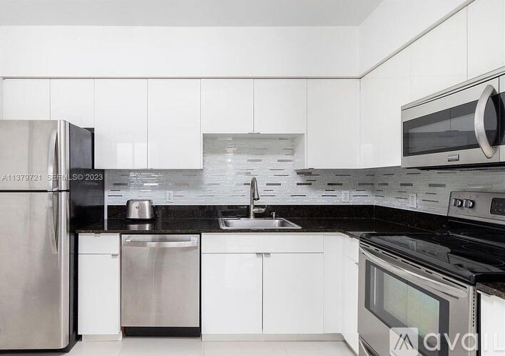 A modern kitchen with white cabinets and stainless steel appliances.