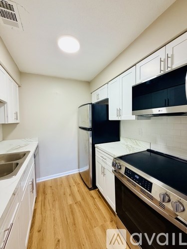 A kitchen with white cabinets and a black fridge.