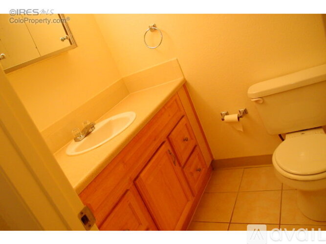A bathroom with a toilet, sink, and wooden cabinets.